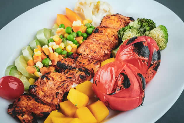 Piatto con pollo grigliato, broccoli, pomodori e verdure colorate: un esempio di pasto sano e bilanciato